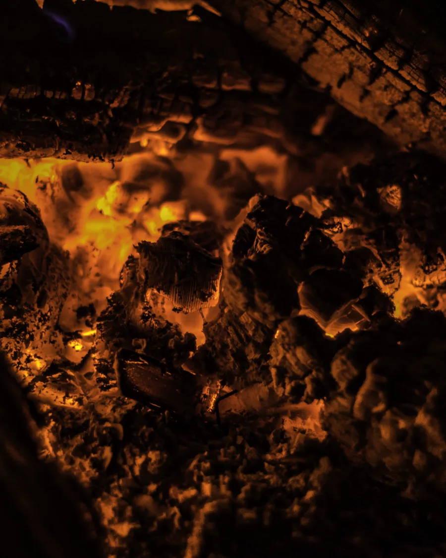 A deep bed of orange coals in the base of a firebox.