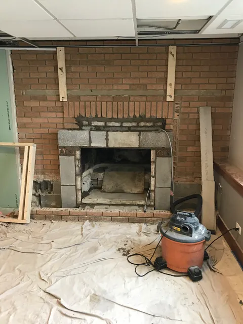 The same fireplace partway through the job, with the brick face taken down around the opening.