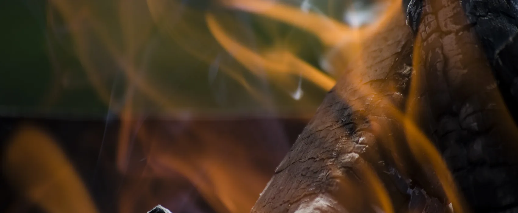 Flame curling around a charred log.