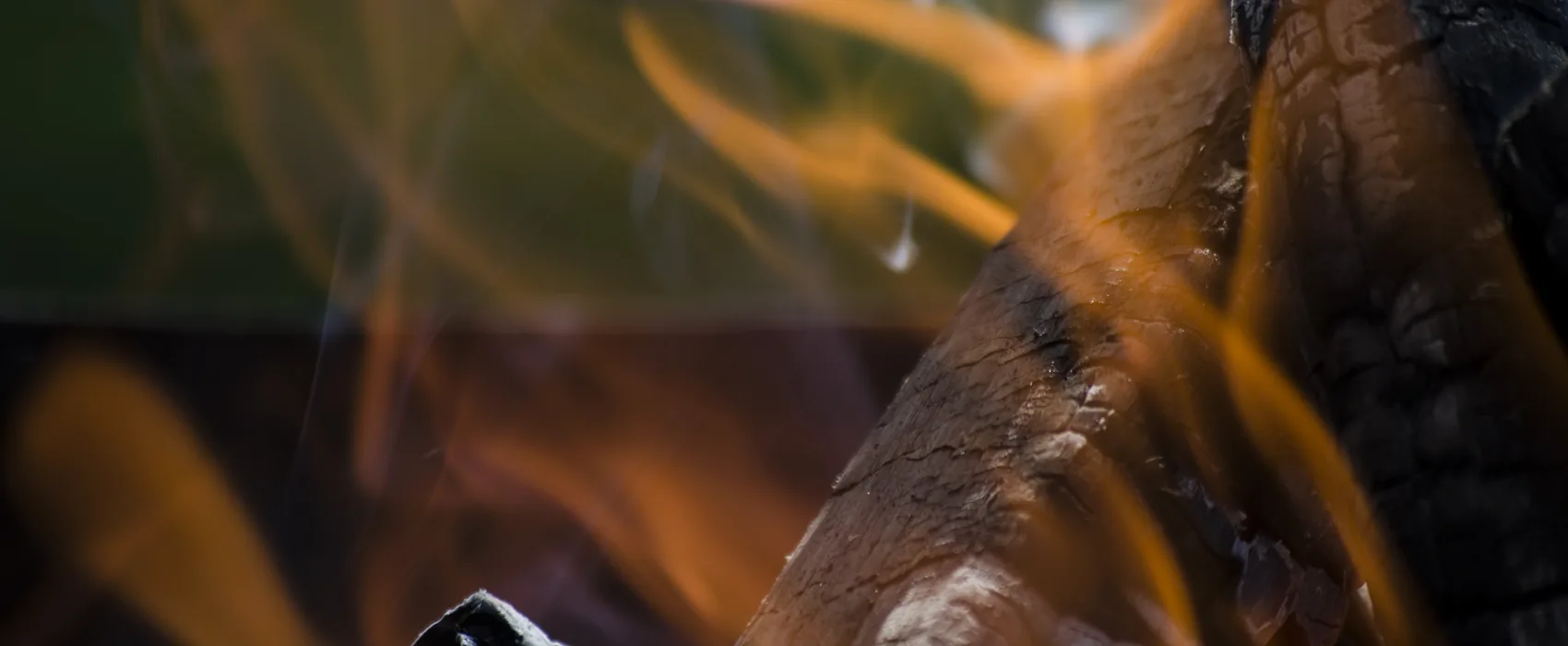 Flame curling around a charred log.
