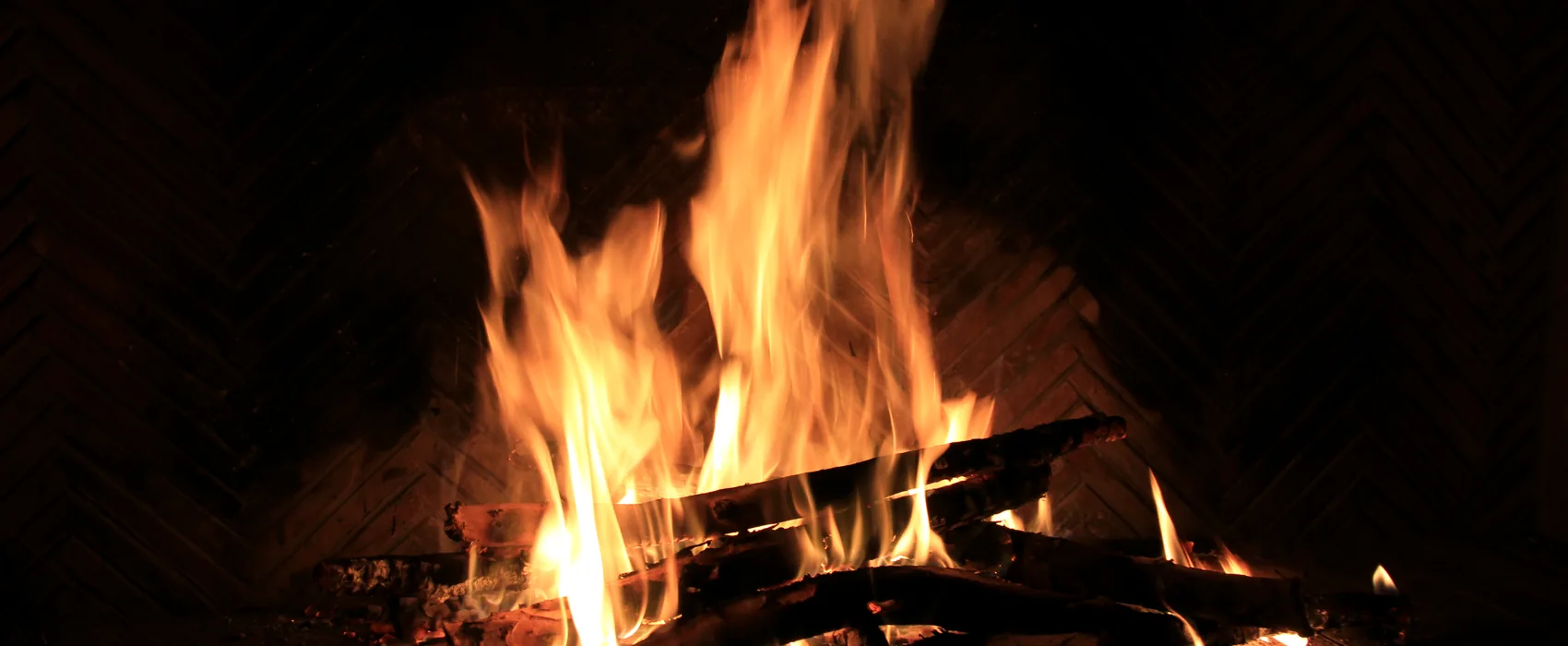 A wood fire burning against dark brick.